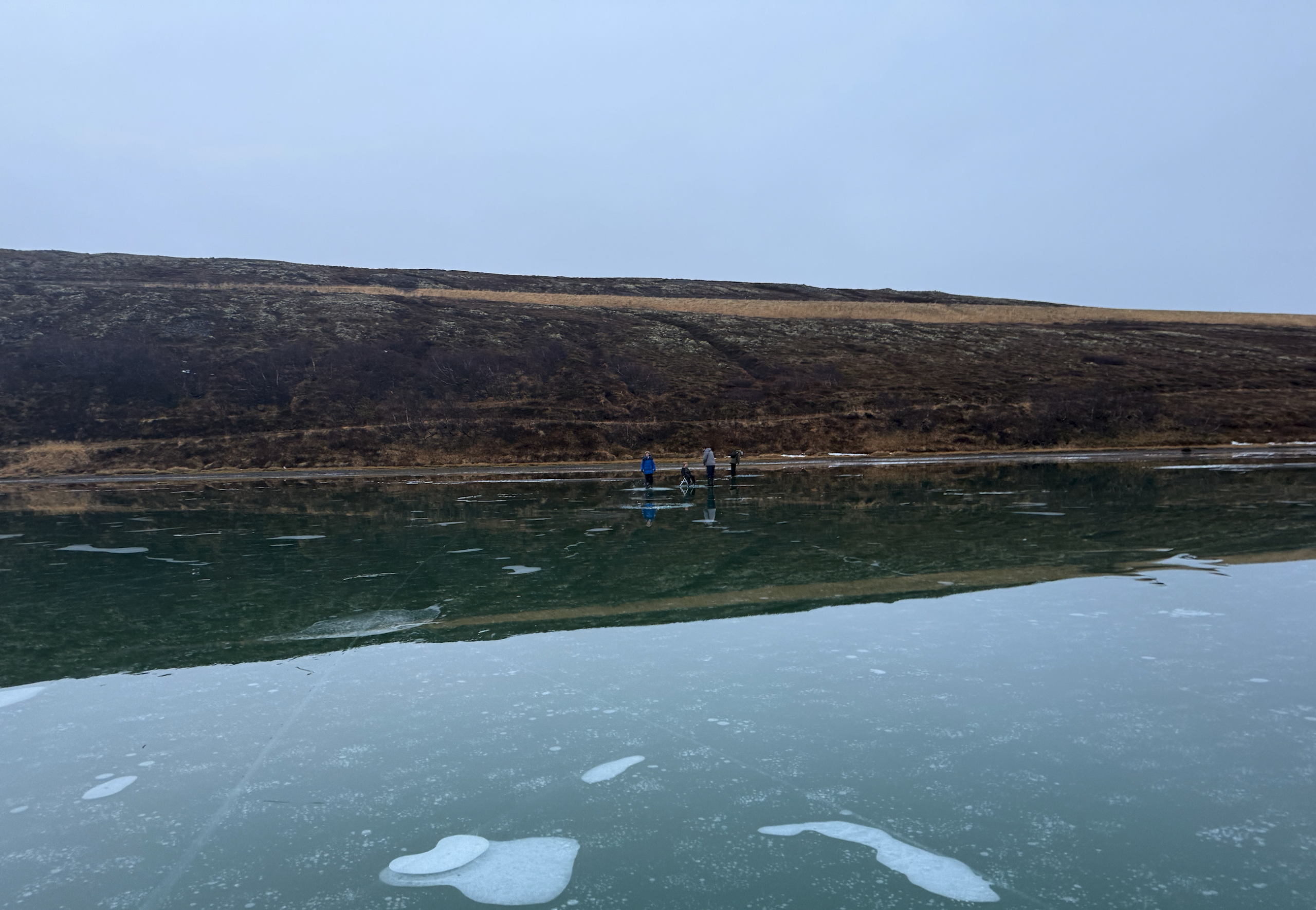 People ice fishing on a frozen lake in iceland