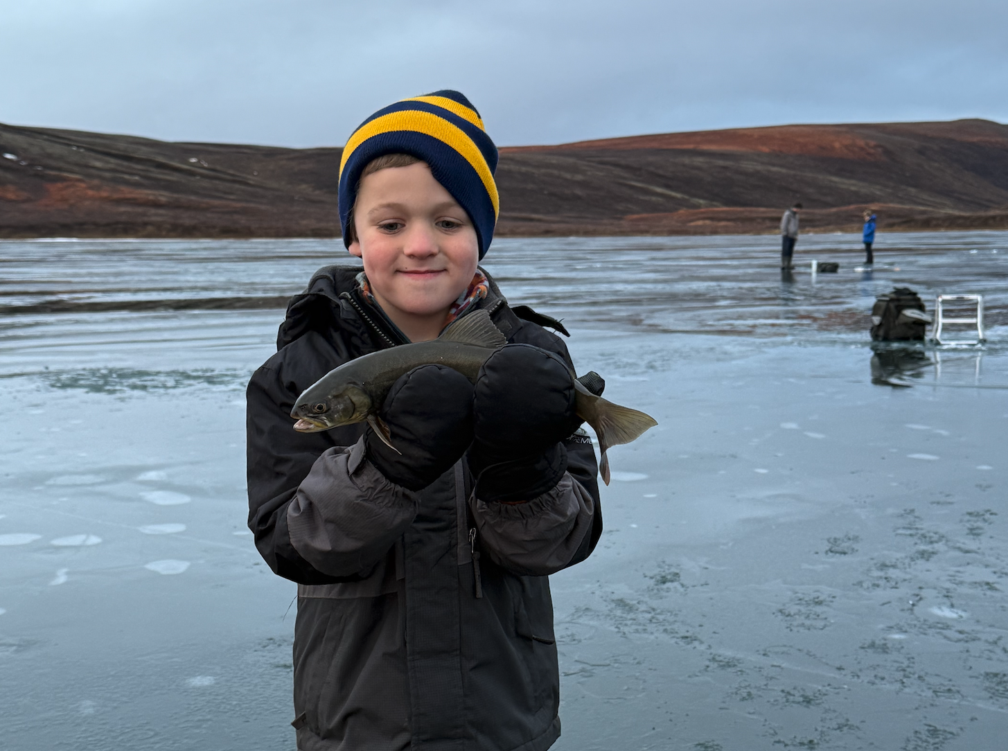 Young angler with an arctic char he caught whiele ice fishing in Iceland